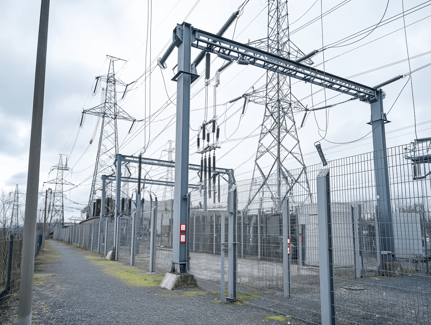 A high-voltage substation with transmission pylons and power lines under an overcast sky
